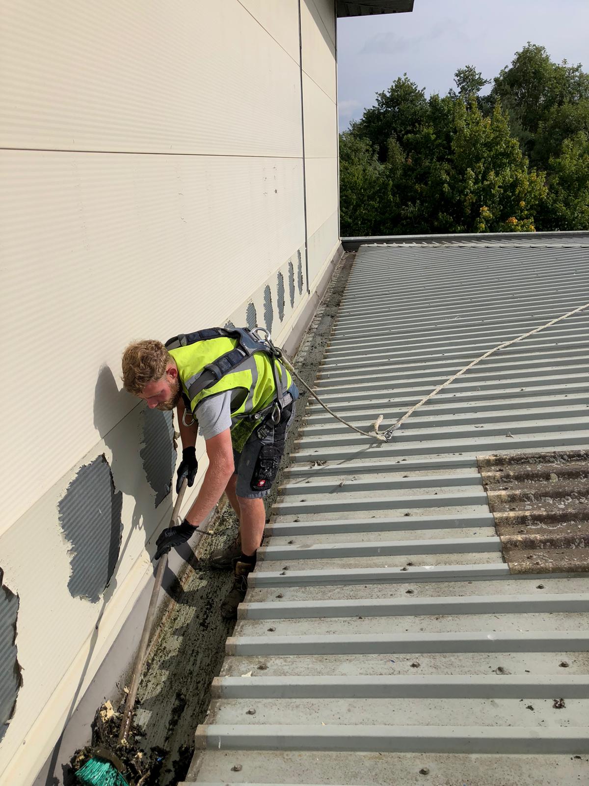 Clearing and repairing gutters as part of commercial roof maintenance